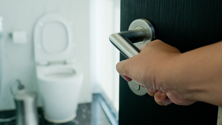 Hand opening door to bathroom