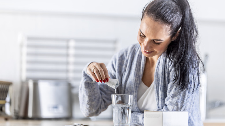 A woman pouring a magnesium powder into a glass of water