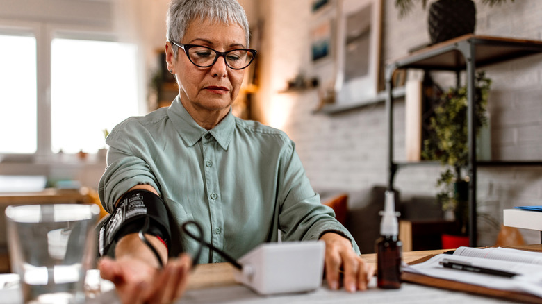 A woman checkin her blood pressure at home