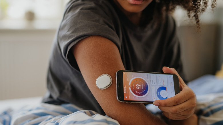 A young girl using her smartphone to test her blood sugar