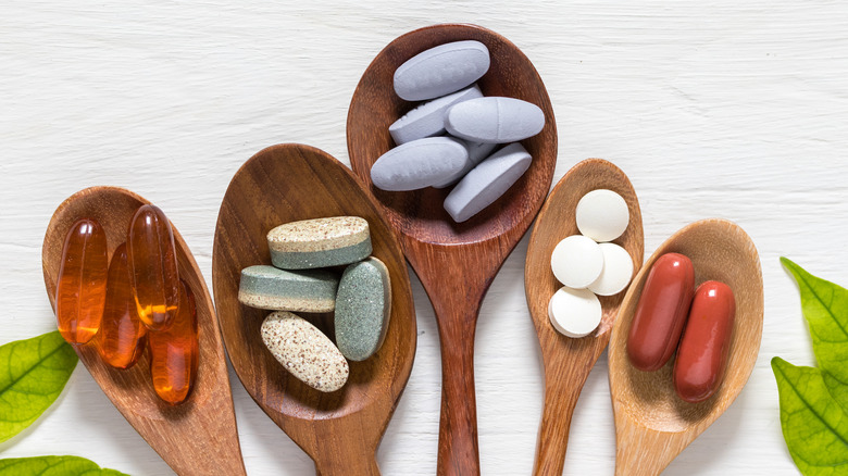 various supplement pills in wooden spoons