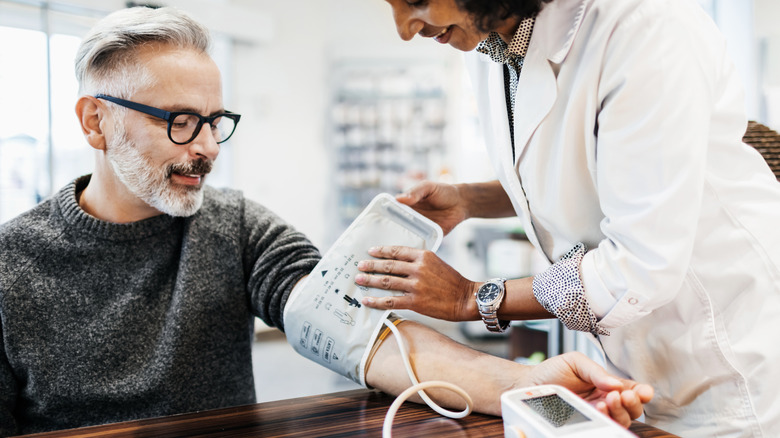 A man getting his blood pressure checked by a pharmacy technician