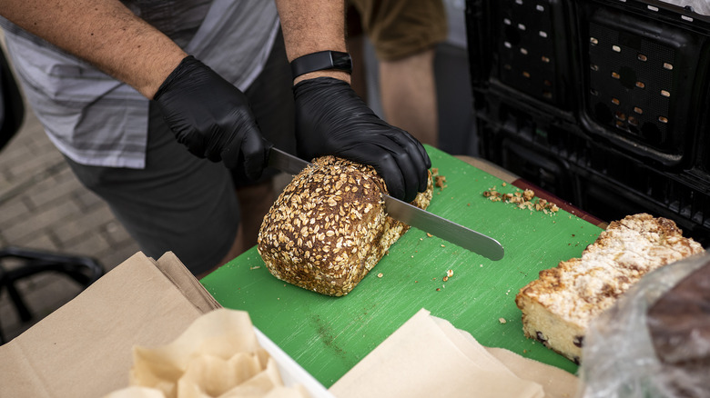 Worker cutting a loaf of bread