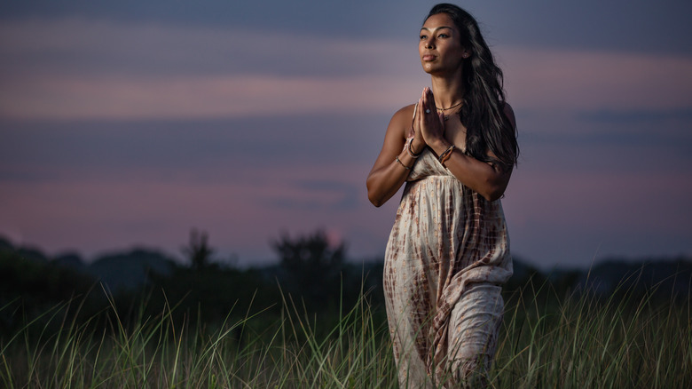 Thara Natalie stands outside with her hands in prayer