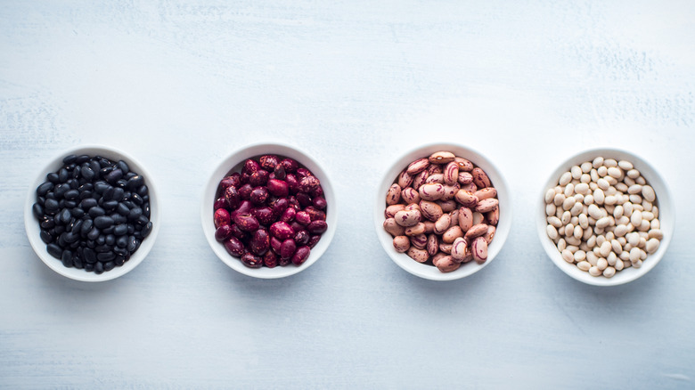 Top view of bowls with black, red, pinto, and white beans