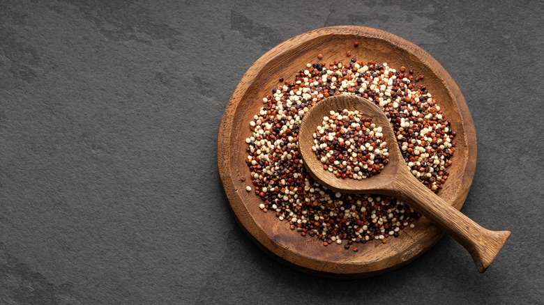 Mix of white, red and black quinoa seeds in wooden bowl