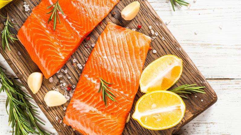 Top view of fresh salmon fillet on a cutting board with ingredients for cooking