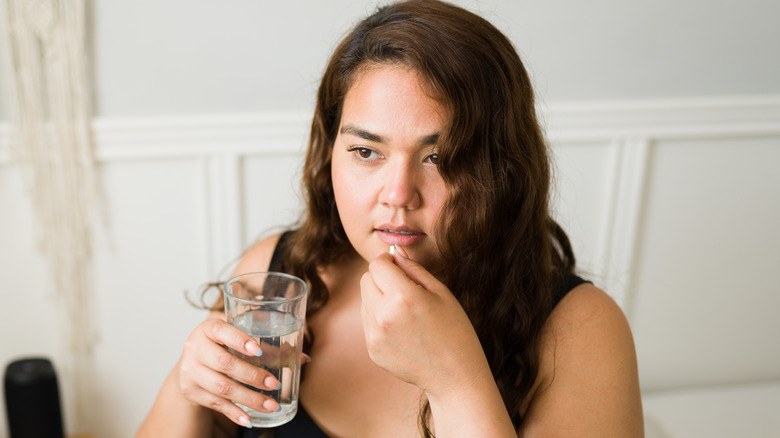 Woman swallowing a pill with a glass of water