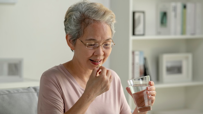 Senior woman swallowing medication with water