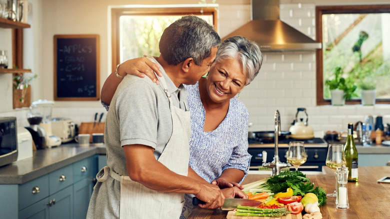 older couple smiling cutting vegetables