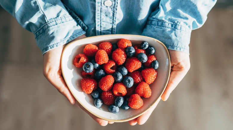 hands holding bowl of berries