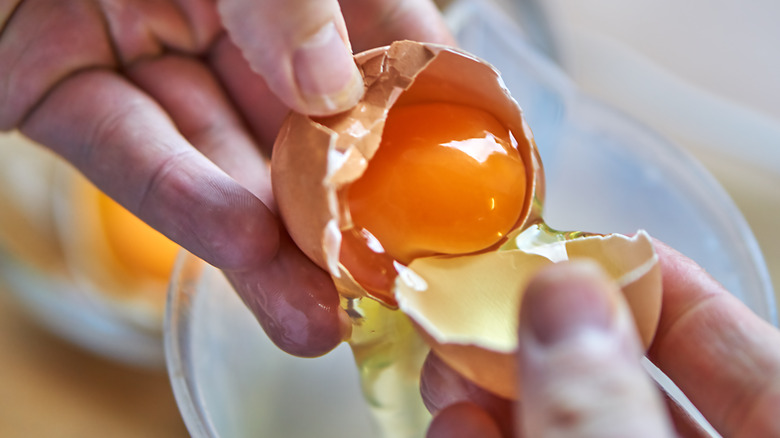 A man eating eggs with bacon, toast, and orange juice