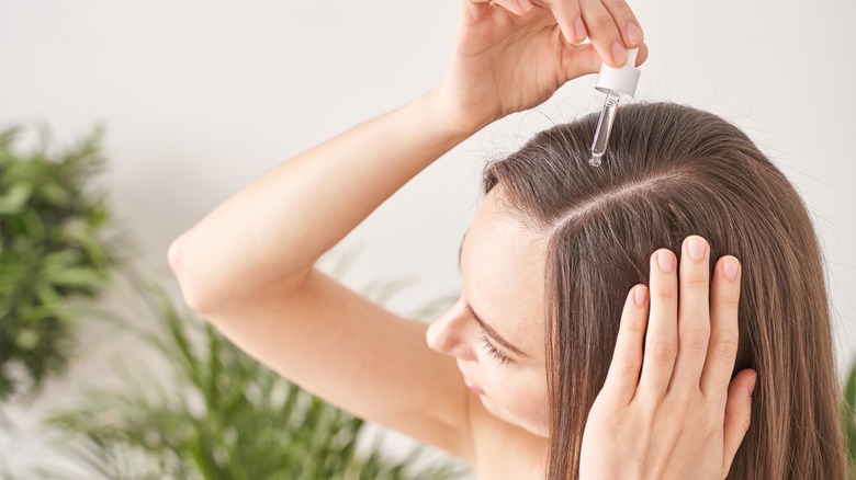 Woman applying serum to hair