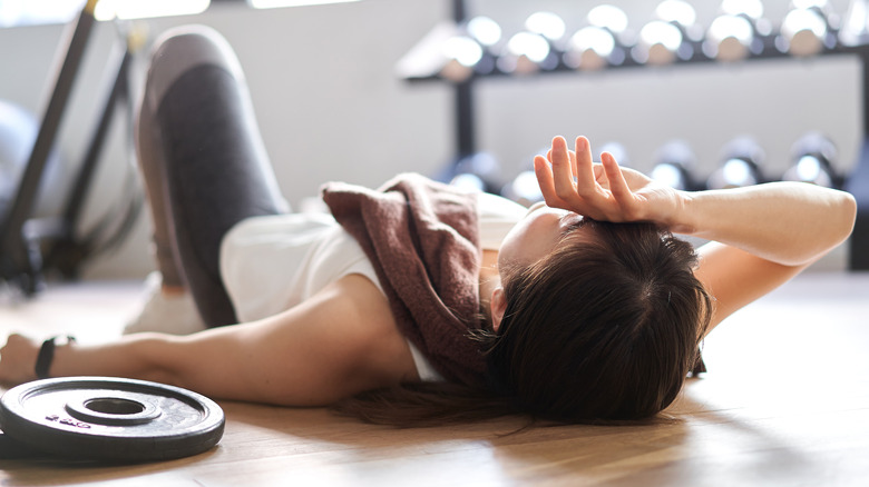 fatigued woman lying on gym floor