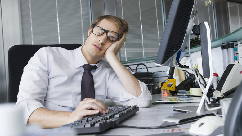 A man asleep at his office computer