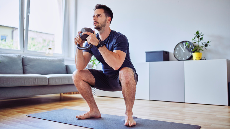 Man doing squats with kettlebell