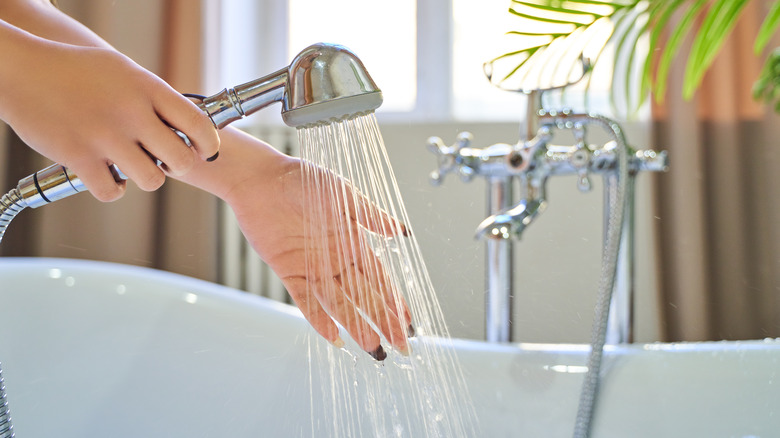 a hand touches shower water