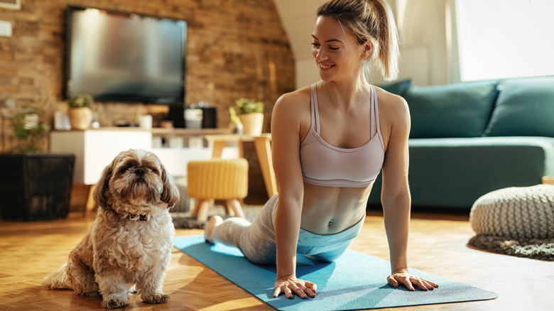 woman doing cobra pose with dog