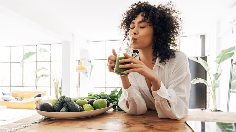 woman drinking green beverage