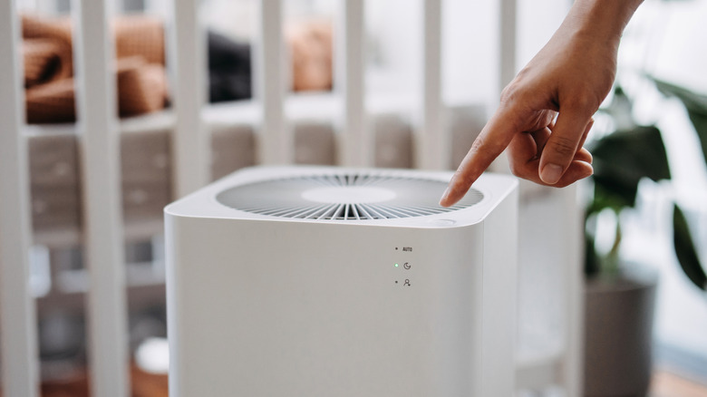 A woman's hand turning on an air purifier in her child's room