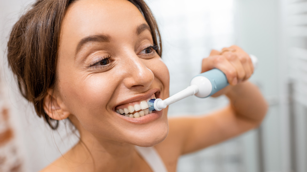 woman using electric toothbrush