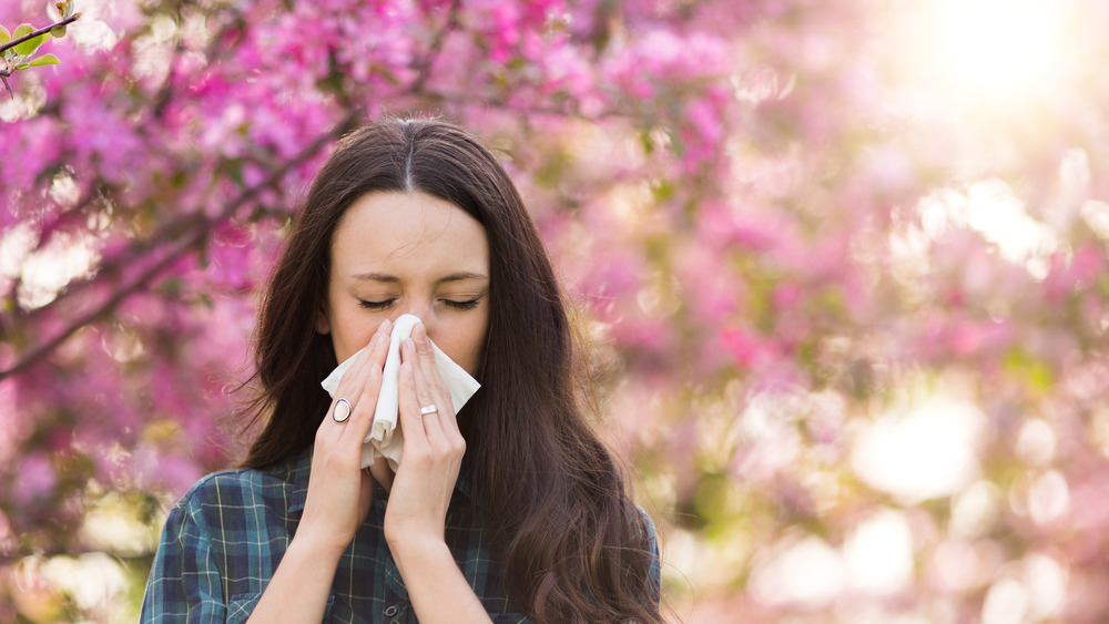 woman sneezing outdoors