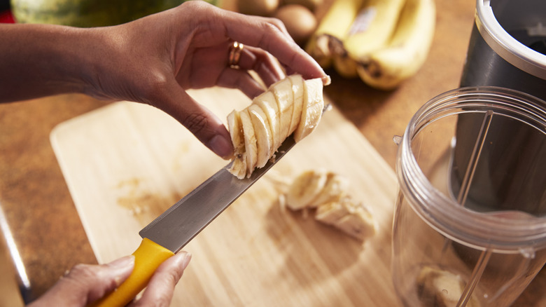 A person in a kitchen preparing a banana smoothie