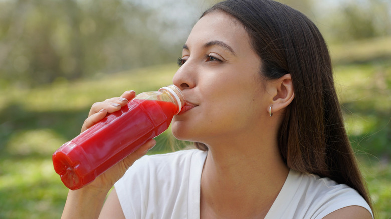 A woman sitting outside drinking beet juice