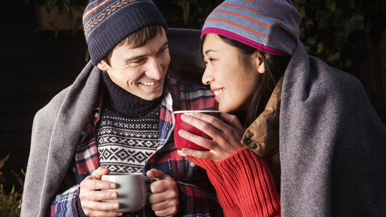 A man and woman sitting together and drinking hot cocoa