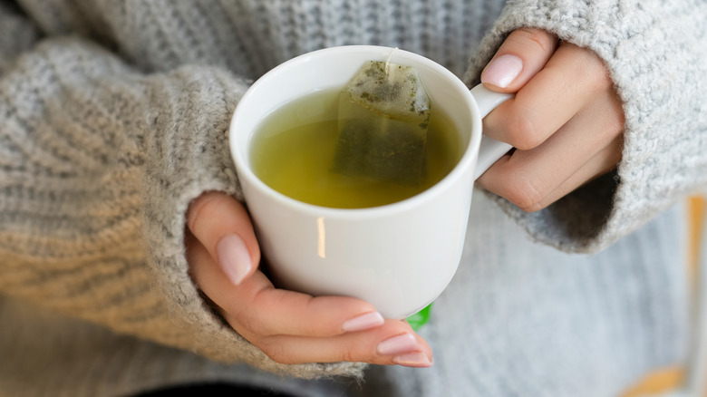 A woman holding a mug of green tea