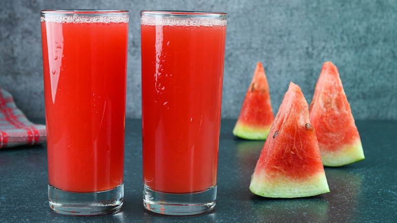 Glasses of watermelon juice with watermelon slices in the background