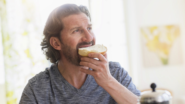 A man eating a bagel with cream cheese