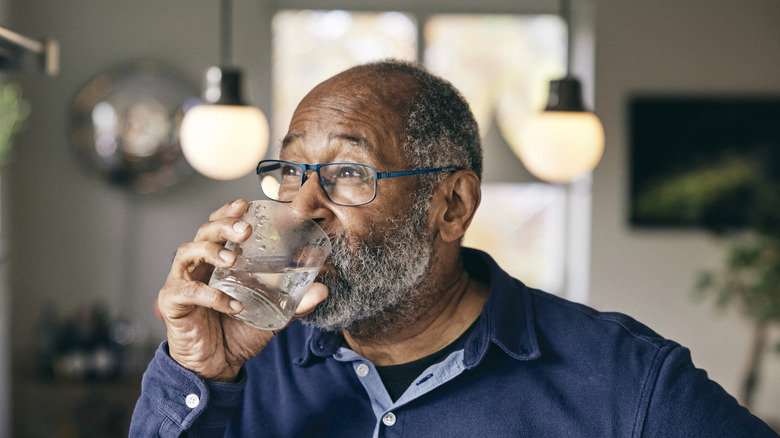 An older man drinking a glass of water