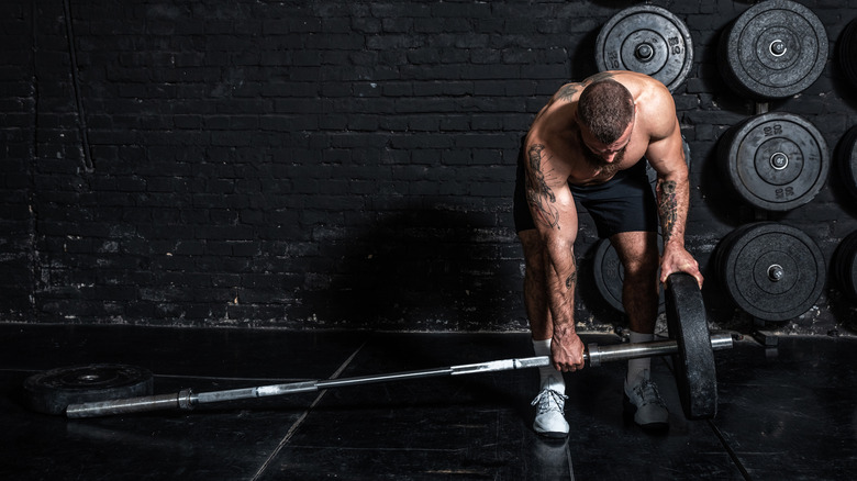 man putting weights on barbell