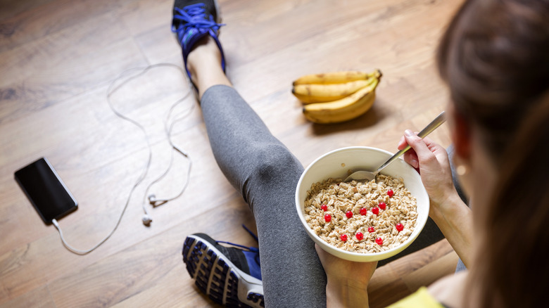 A woman eats a bowl of oatmeal after she works out