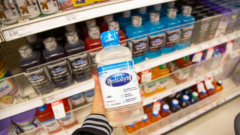 Person holding bottle of pedialyte grabbed from grocery store shelf