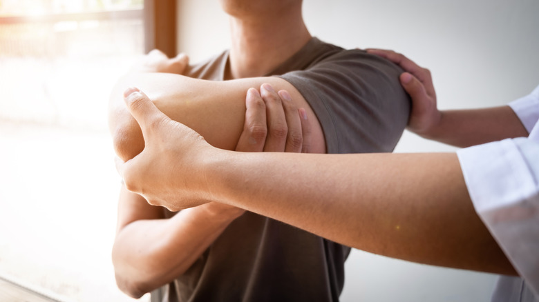 Hands holding man's shoulder and arrm