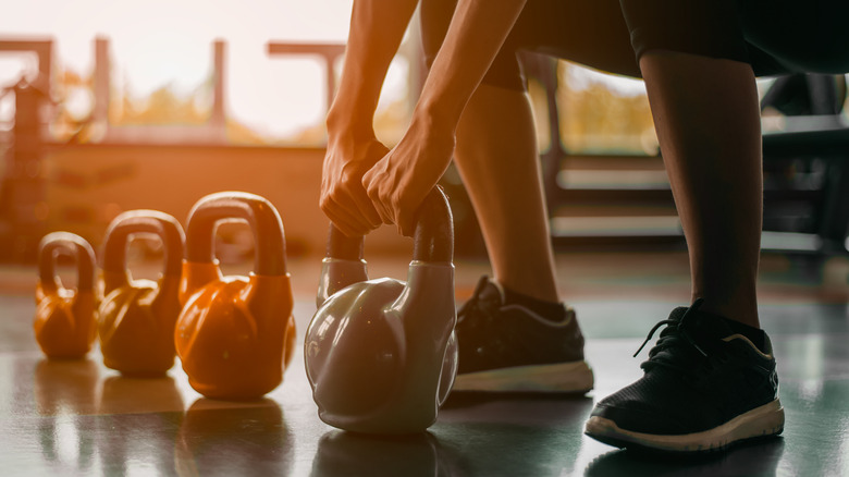 Person gripping kettlebell inside gym