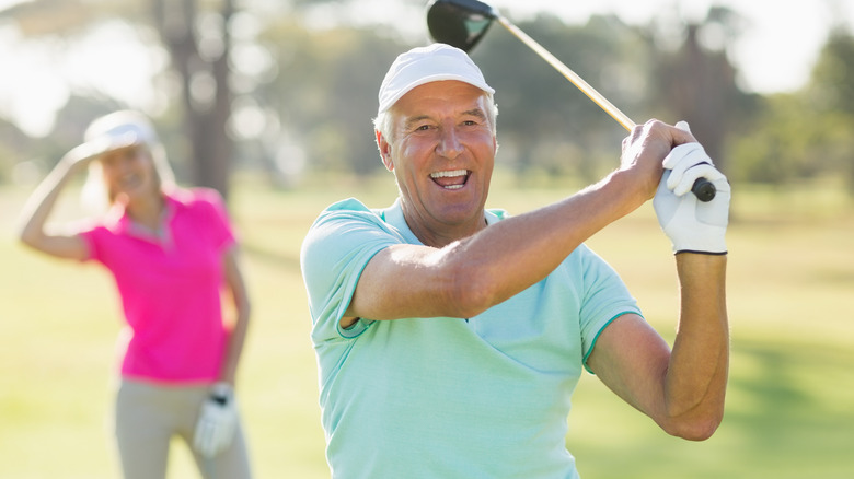 Smiling man with golf club on course