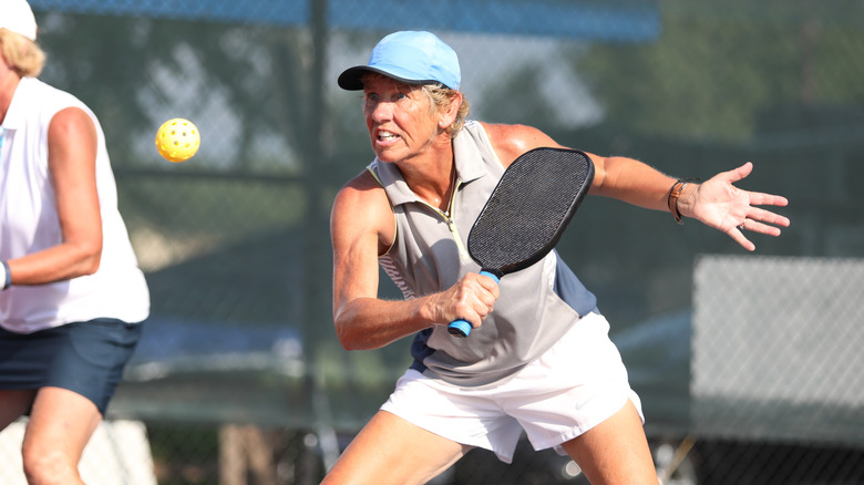action woman with pickleball racket and ball