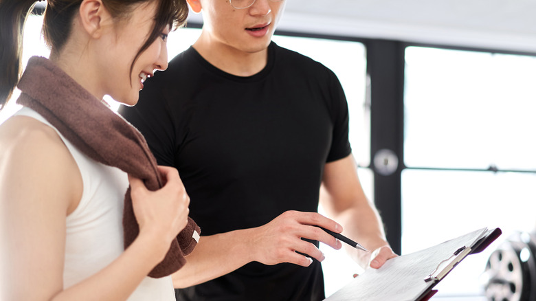 Woman and trainer discussing fitness plan 