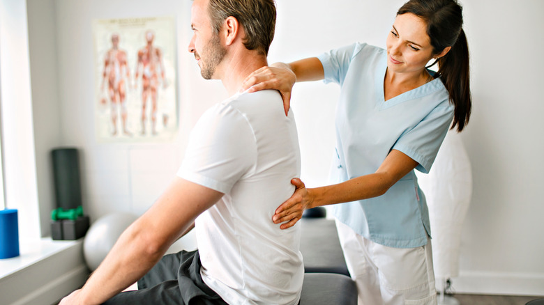 physical therapist addressing patient with back pain