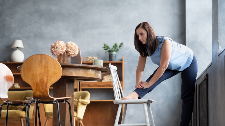 woman stretching hamstring by using a chair