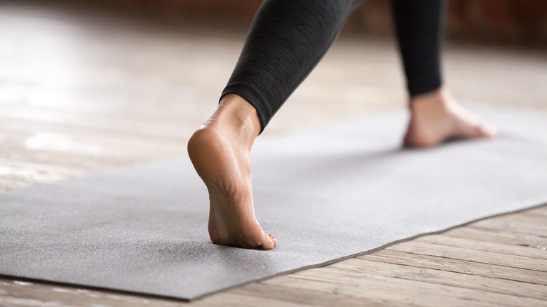 split stance of legs on yoga mat