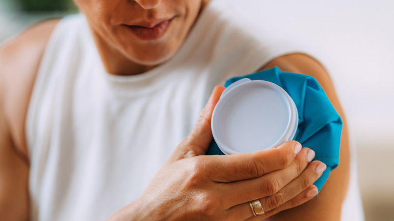 woman holding ice on shoulder