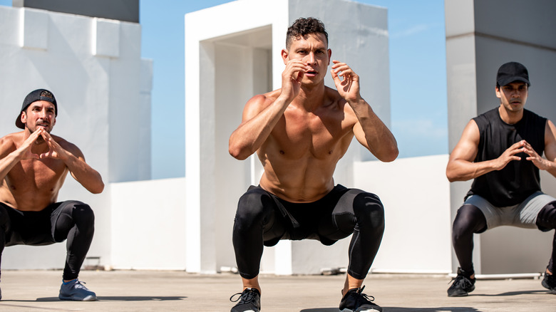 men squatting in open outdoors space