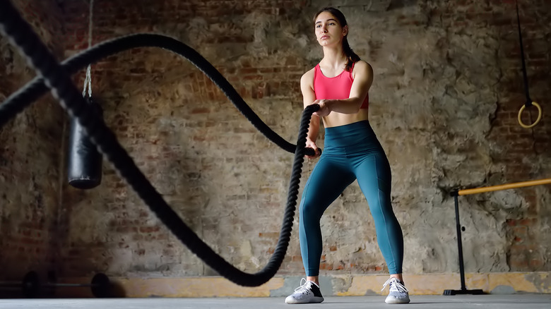 Fit woman training with battle ropes