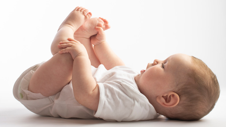 baby lying down holding feet 