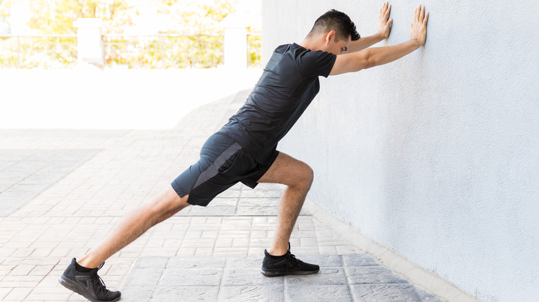 man performing wall calf stretch