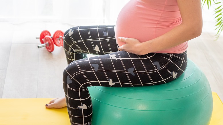 pregnant woman sits on birthing ball